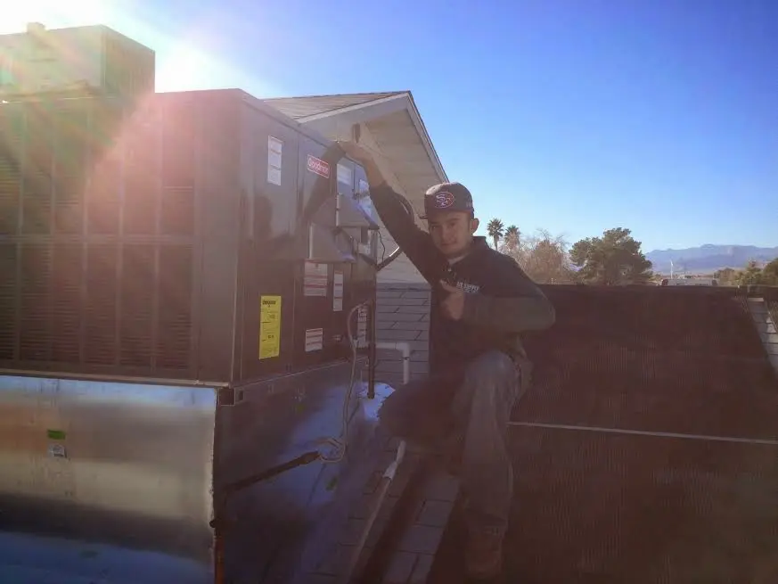 HVAC technician performing AC Tune-Up on a rooftop unit in Moore